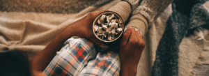 personne profitant du hygge en hiver avec un pyjama douillet et une boisson chaude